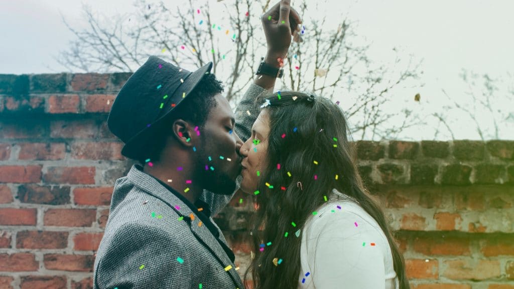 Couple mixte s'embrassant sous une pluie de confettis