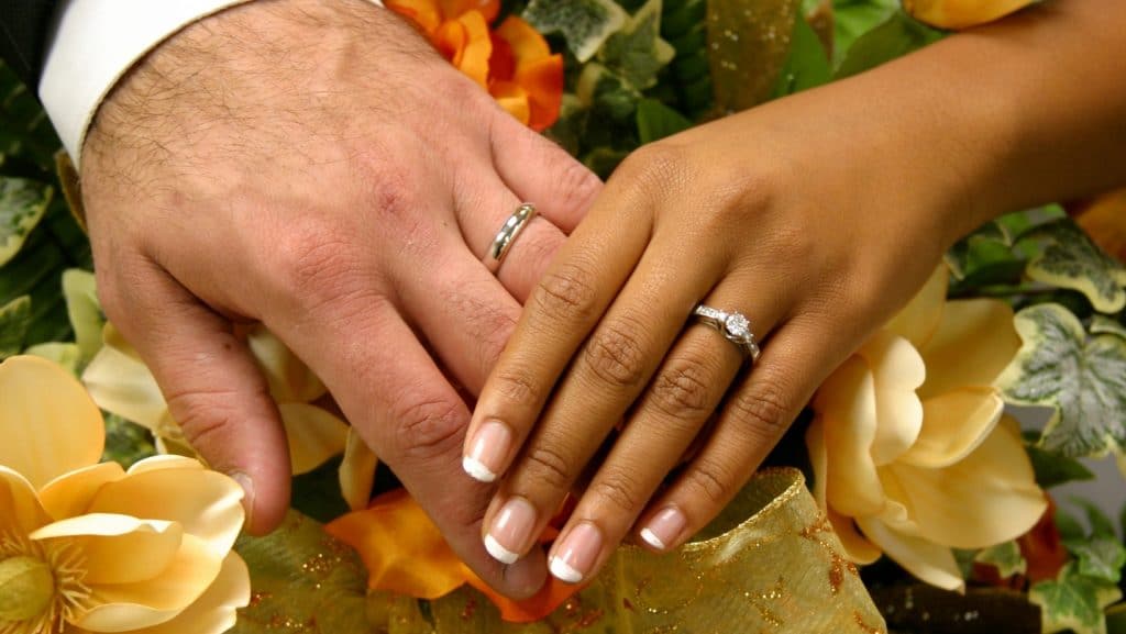 Photos des mains d'un couple mixte avec leurs alliances